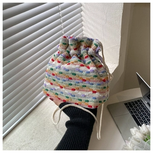 Detail of colorful woven drawstring bucket bag with textured multi-color knit patterns