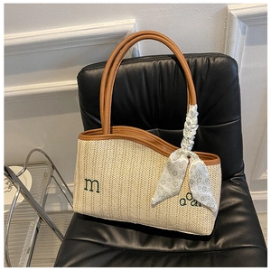 Detail of hand-woven straw tote with leather handles and embroidered letters m and Q