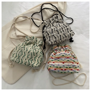 Detail of woven bucket bags with drawstring closure in multiple colors on a blazer