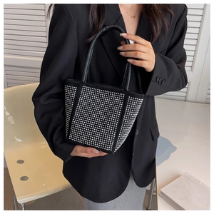 Close-up of a black bucket bag with sparkling silver rhinestones and a round leather handle