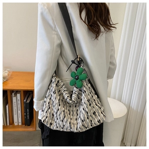 Detail of large woven tote bag in black and white stripes with green floral charm
