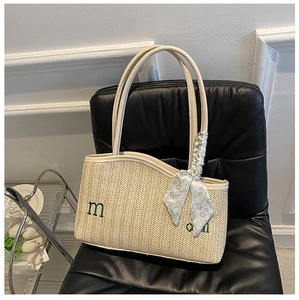 Detail of beige straw tote bag with embroidered letters and floral silk scarf accessory