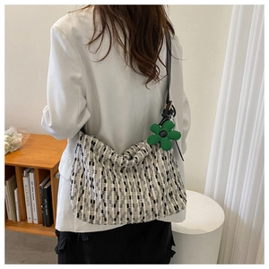 Detail of woven tote bag with black and white stripes and green flower pendant