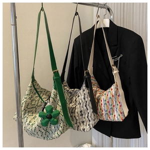 Detailed view of woven tote bags in three colors hanging on a silver metal rack
