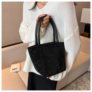 Detailed macro view of a black rhinestone bucket bag with elegant leather handles
