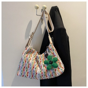 Close-up of colorful wave knit tote bag with wide strap and floral charm detail