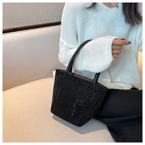 Close-up of black rhinestone bucket bag with crystal detailing and leather handle