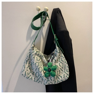 Detail of hobo bag in green tweed texture with leather strap and floral charm