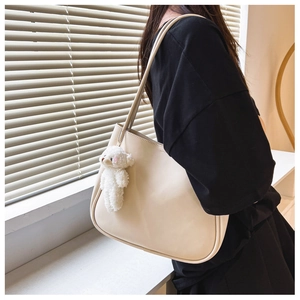 Detail of soft cream PU leather tote bag with a cute plush bear charm on double straps