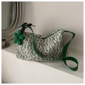 Detail of woven tweed tote bag in green and white with floral charm and leather strap