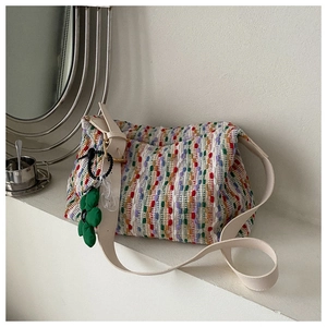 Detail of colorful woven tote bag with adjustable cream faux leather strap and flower charm