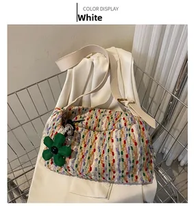 Detail of multi-colored woven tote bag with white leather strap and flower charm accessory