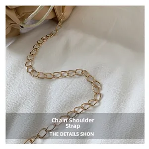 Detail of elegant gold chain shoulder strap on beige drawstring crossbody leather bag