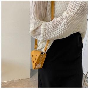 Detailed view of cheese-shaped yellow crossbody bag with mouse charm and metal strap buckle