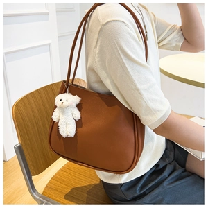 Macro view of soft brown leather tote bag detail with a cute white plush bear charm