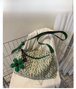 Detail of woven tote bag with green leather strap and floral charm in shopping cart