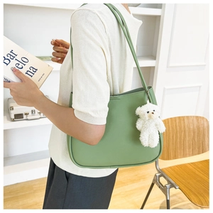 Detail of light green leather tote bag with cute white plush bear charm on the strap