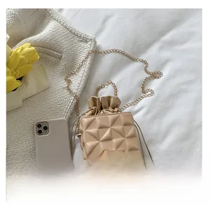 Detail of beige quilted bucket bag showing chain strap and drawstring closure