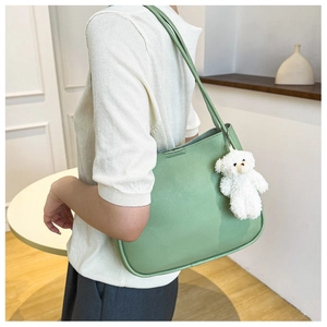 Detailed side view of soft green tote bag with white plush bear charm accessory