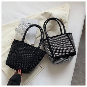 Detail of silver and black rhinestone bucket bags placed on a white blazer with books