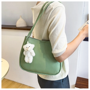 Detail of sage green faux leather tote bag with a cute white plush bear pendant