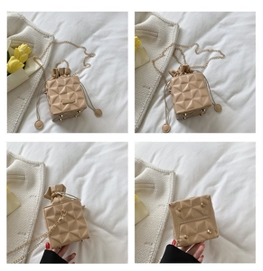 Detail view of apricot quilted bucket bag with chain strap and protective metal feet