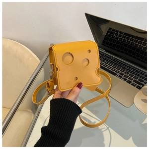 Detailed view of yellow cheese-shaped crossbody bag with realistic cutout holes