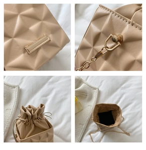 Detail view of beige bucket bag featuring geometric texture and gold chain strap