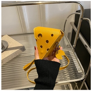 Detail of yellow cheese-shaped mini crossbody bag with leather texture and smiley pendant