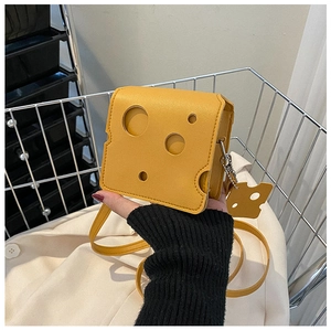 Detail of yellow cheese-shaped crossbody bag with hollow holes and a small charm