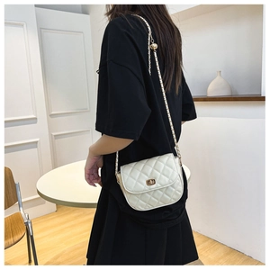 Close-up of quilted cream crossbody bag with adjustable gold chain and metal lock