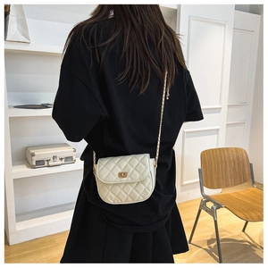Rear view of a model wearing the cream quilted crossbody bag with chain strap