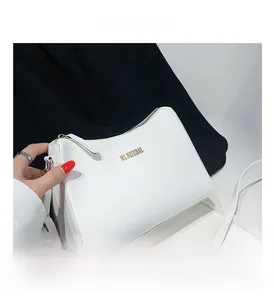 Detail shot of white matte faux leather handbag with gold zipper and long shoulder strap