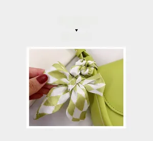 Detailed shot of lime green leather handbag with a chic green and white checkered silk scarf