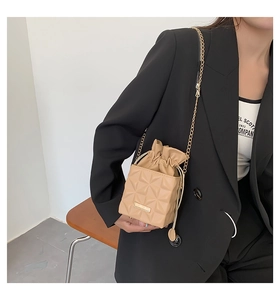 Detailansicht einer beigen gesteppten Beuteltasche mit goldenem Kettenträger