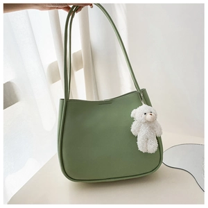 Detail of light green PU leather shoulder bag with a cute white plush bear charm