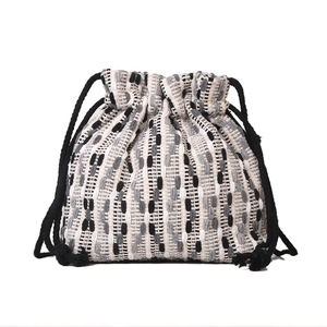 Minimalist drawstring bucket bag with black and white woven vertical stripe patterns