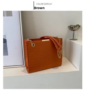 Vue détaillée du sac cabas marron à motif crocodile avec chaîne dorée et texture