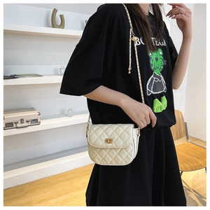 Detail of beige quilted crossbody bag with gold chain strap and metallic turn-lock closure