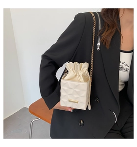 Detail of cream drawstring bucket bag featuring quilted pattern and gold chain strap