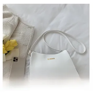Minimalist white leather shoulder bag detail with phone comparison and tulip decor