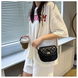 Detailed view of black quilted saddle bag with gold chain strap and metal swivel lock