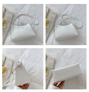 Detail view of a white trapezoid shoulder bag with gold logo and adjustable strap