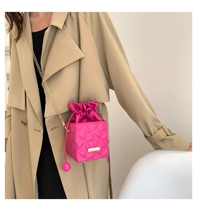 Detail of fuchsia geometric crossbody bag with 3D diamond quilting and drawstring closure