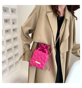 Close-up of fuchsia quilted mini bucket bag with gold chain strap and metal nameplate