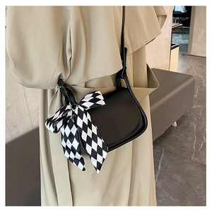 Detail of black leather saddle bag with a stylish checkered silk scarf tied on the strap