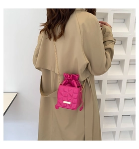 Detail of rose pink quilted mini bucket bag with gold chain strap worn by a model