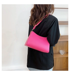 Detail of bright pink leather shoulder bag with gold hardware and brand logo lettering