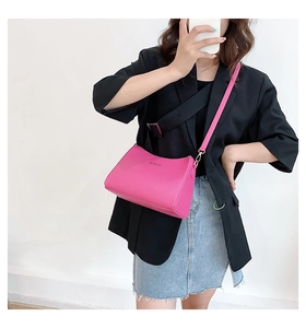 Rose red leather crossbody bag worn by model in black blazer and denim skirt