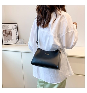 Close-up of a minimalist black leather crossbody bag with elegant gold logo lettering